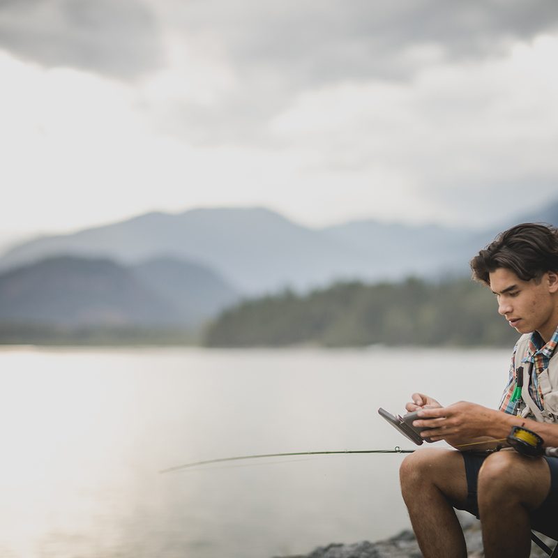 A man fishing by the side of the water
