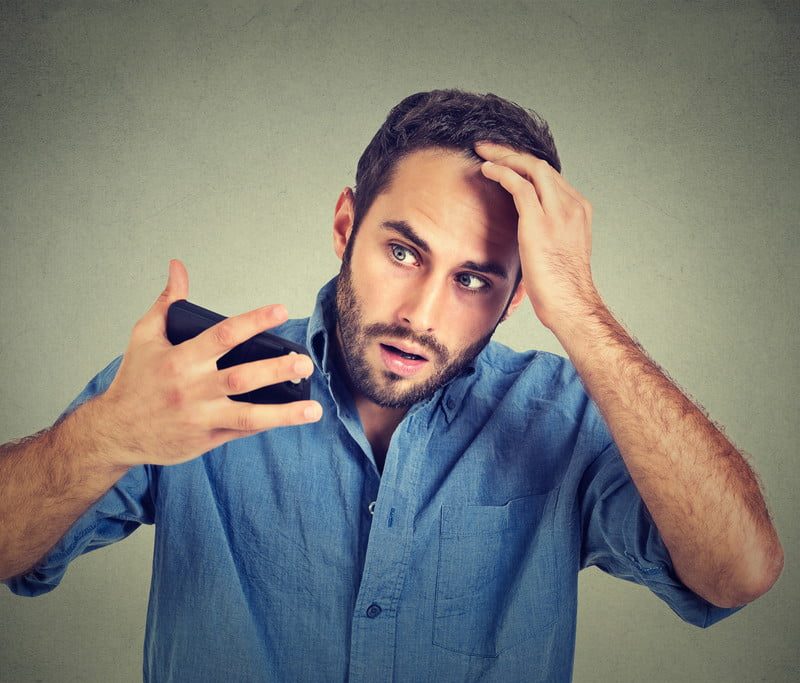 Man looking at his receding hairline.