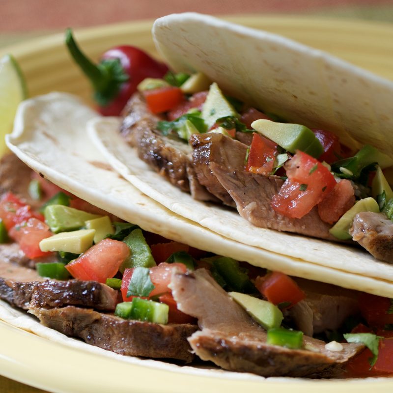 Juicy pork carnitas with fresh salsa of tomato, jalapeno, avocado, onion, and cilantro, garnished with a hot pepper and lime slice