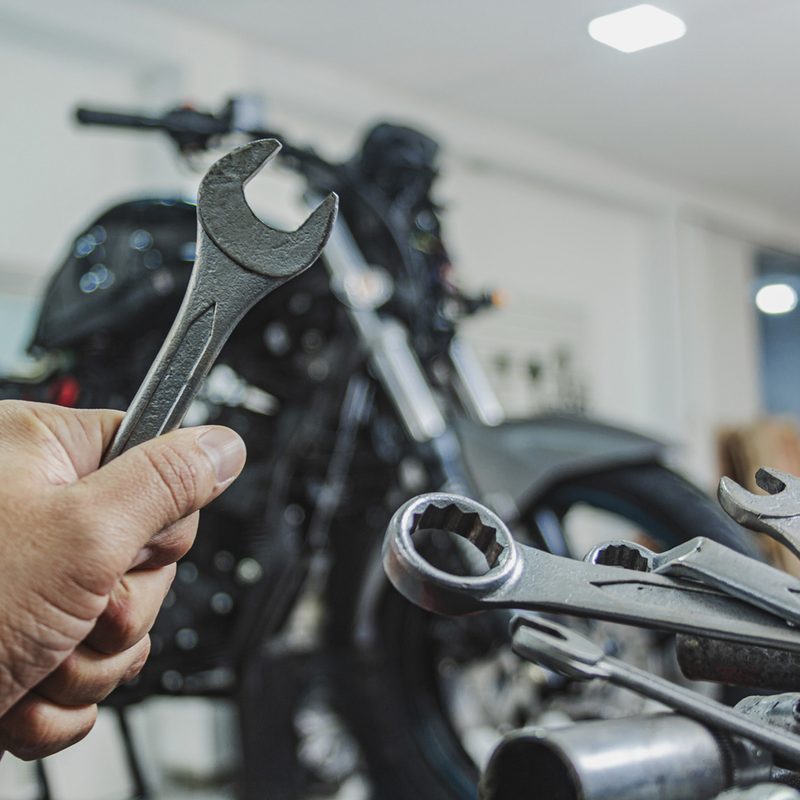 Hand of a mechanic holding a wrench in workshop.