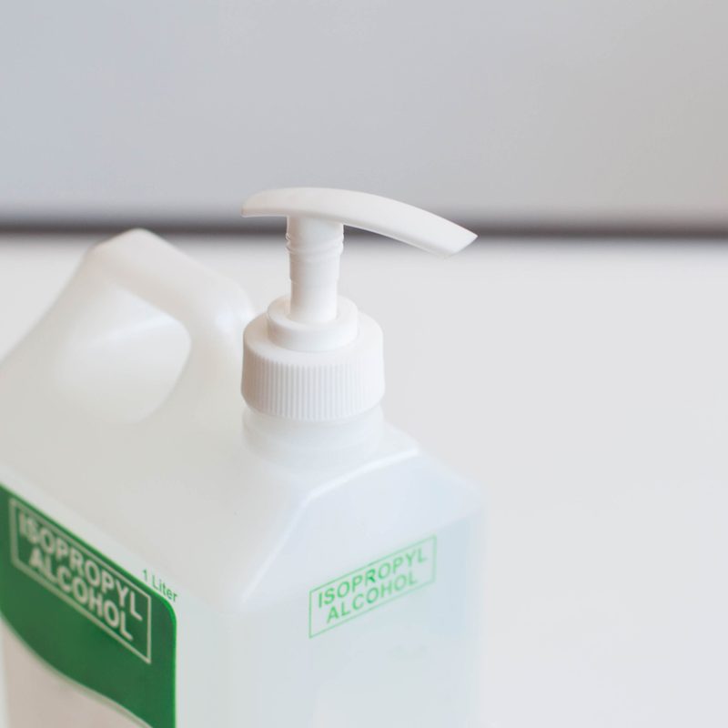 A view of isopropyl alcohol on a plastic dispenser on a white background.