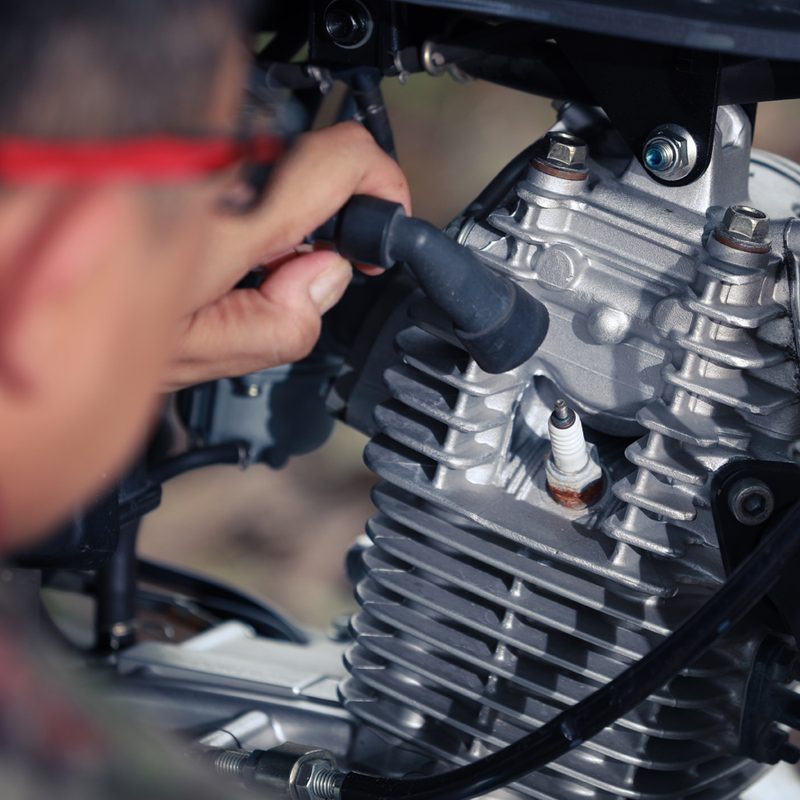 Mechanic man checking a spark plug of vintage motorcycle.
