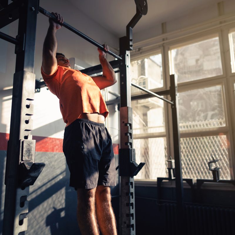 Young man doing pull-ups in a gym.