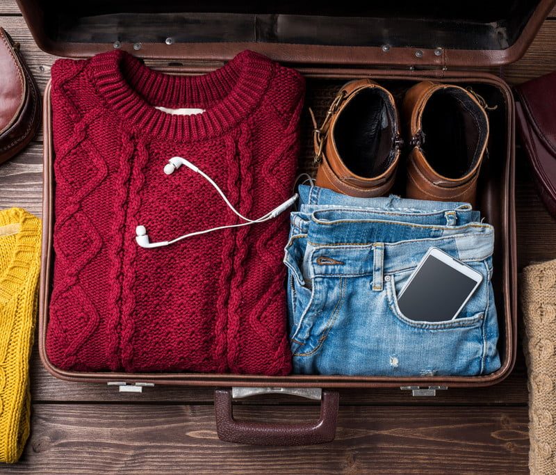 Suitcase with a sweater, jeans, and shoes