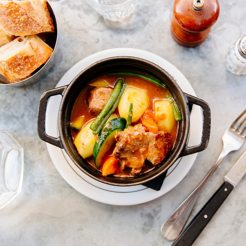 Lamb stew (Navarin) with vegetables served in black cast iron casserole