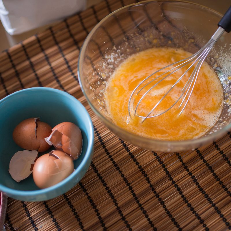 Beaten eggs in a glass bowl on the table.