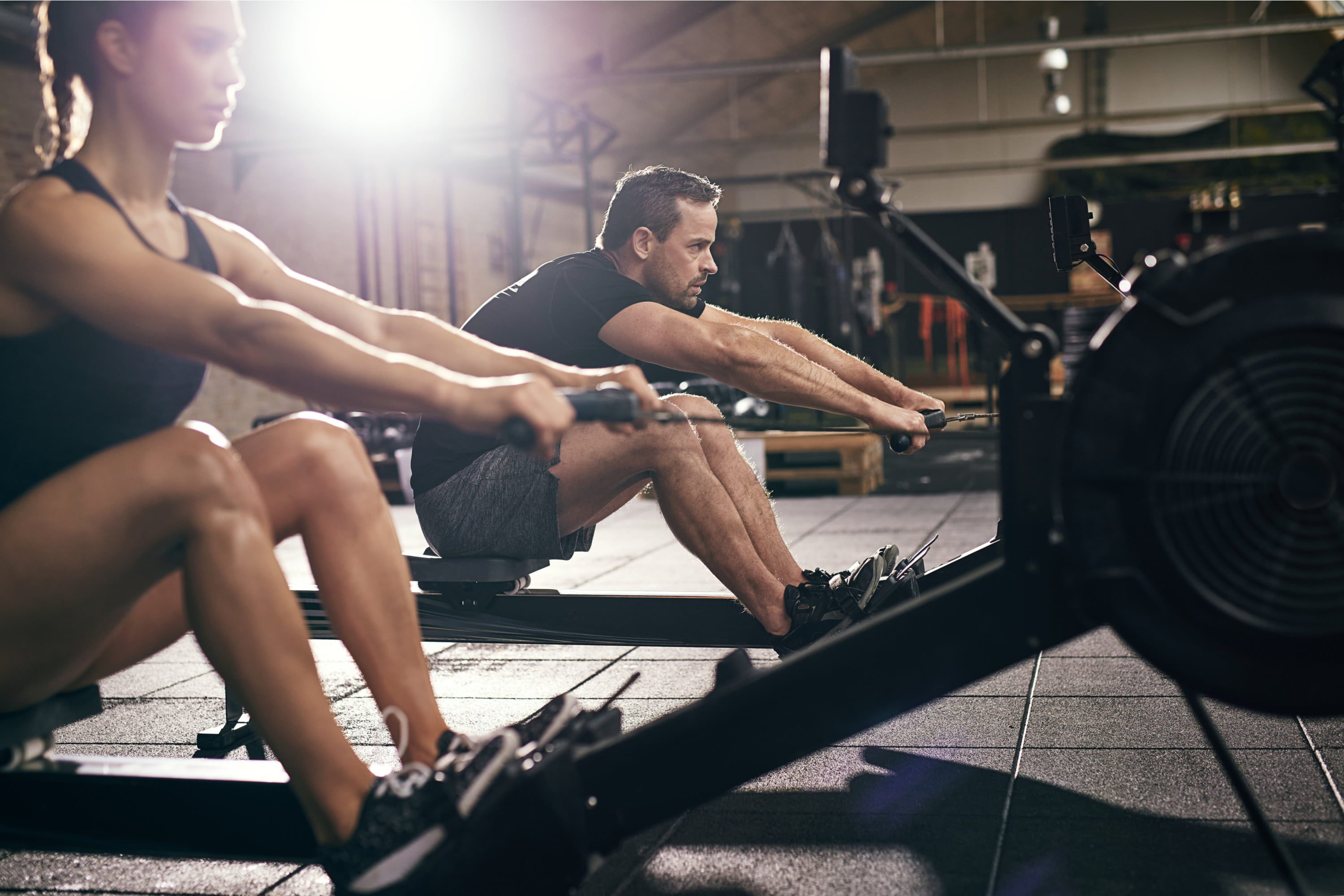 Two people on rowing machines.