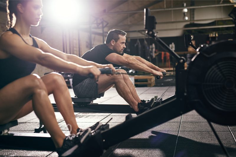 Two people on rowing machines.