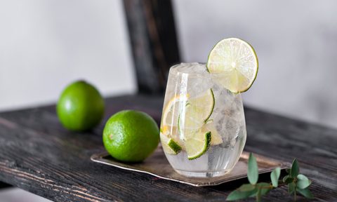 Cold cocktail with lime, lemon, tonic, vodka and ice on vintage background