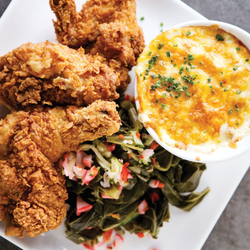 Fried chicken on a plate next to some greens and a dipping sauce, Lucille's - Houston, Texas