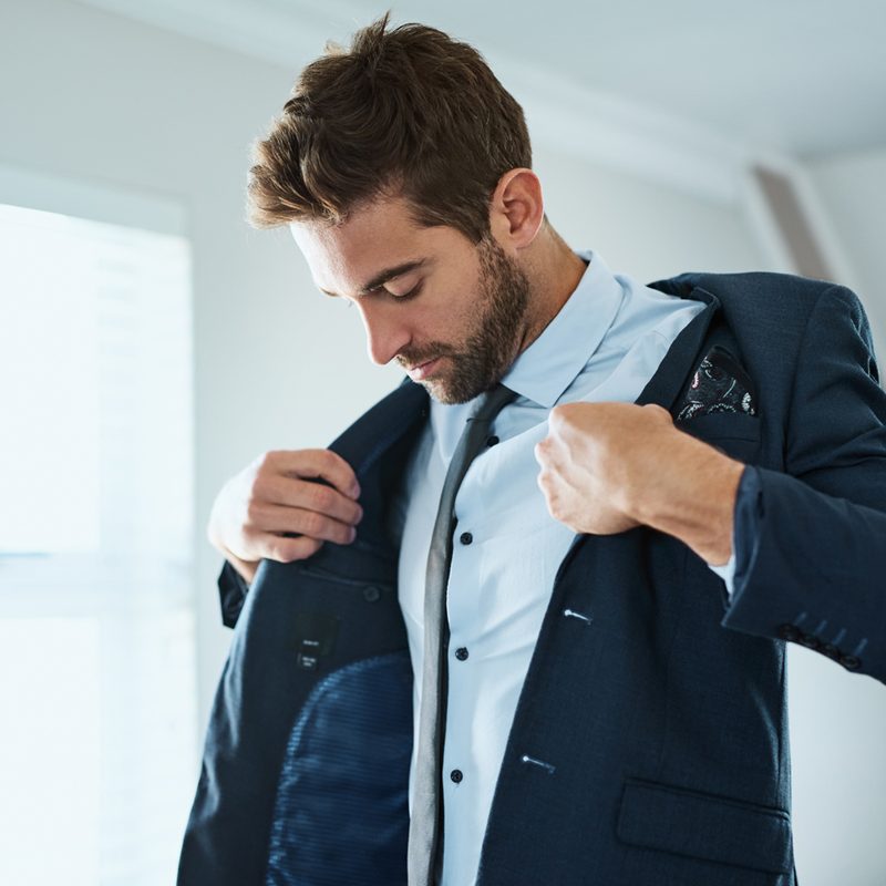 A man putting on his blazer