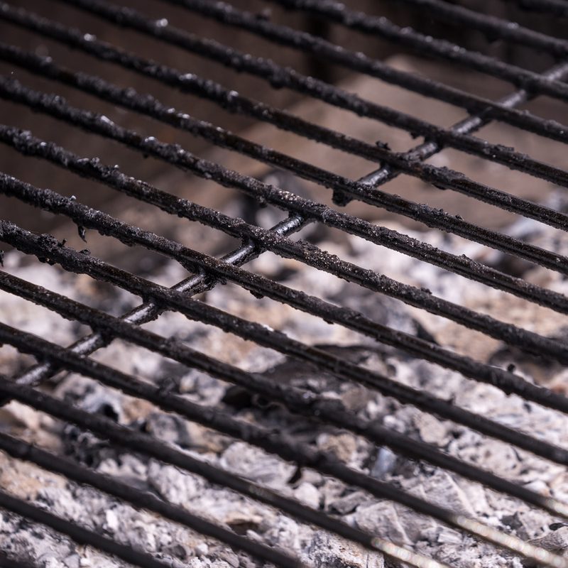 A dirty grill that needs to be sprayed with a cleaner