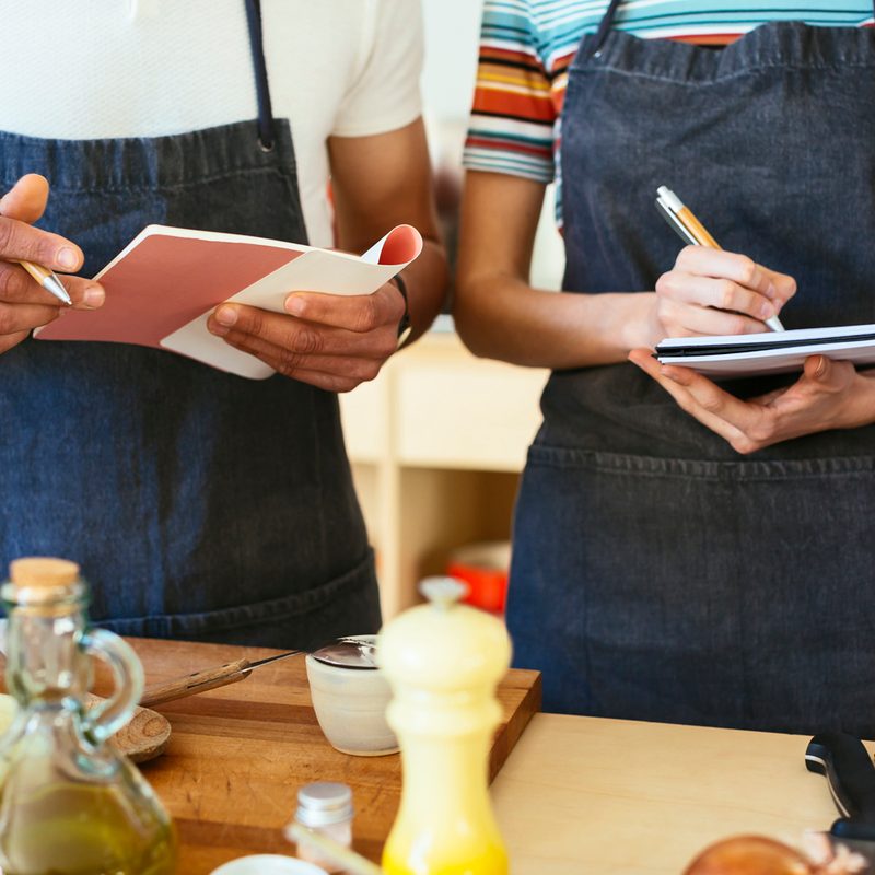 A close-up of a man and woman taking notes during a cooking class.