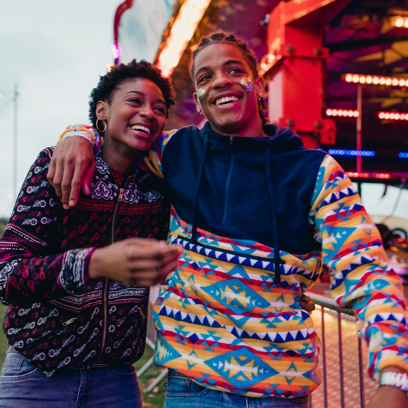 A smiling couple walking around the carnival.