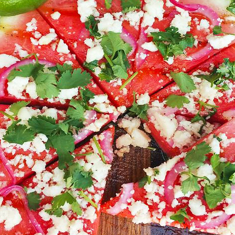 Slices of grilled watermelon pizza with honey and lime on a cutboard.
