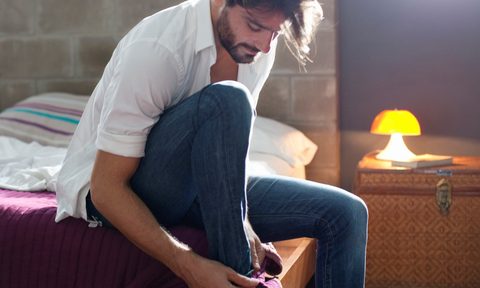 how your jeans should fit man sitting on bed  getting dressed
