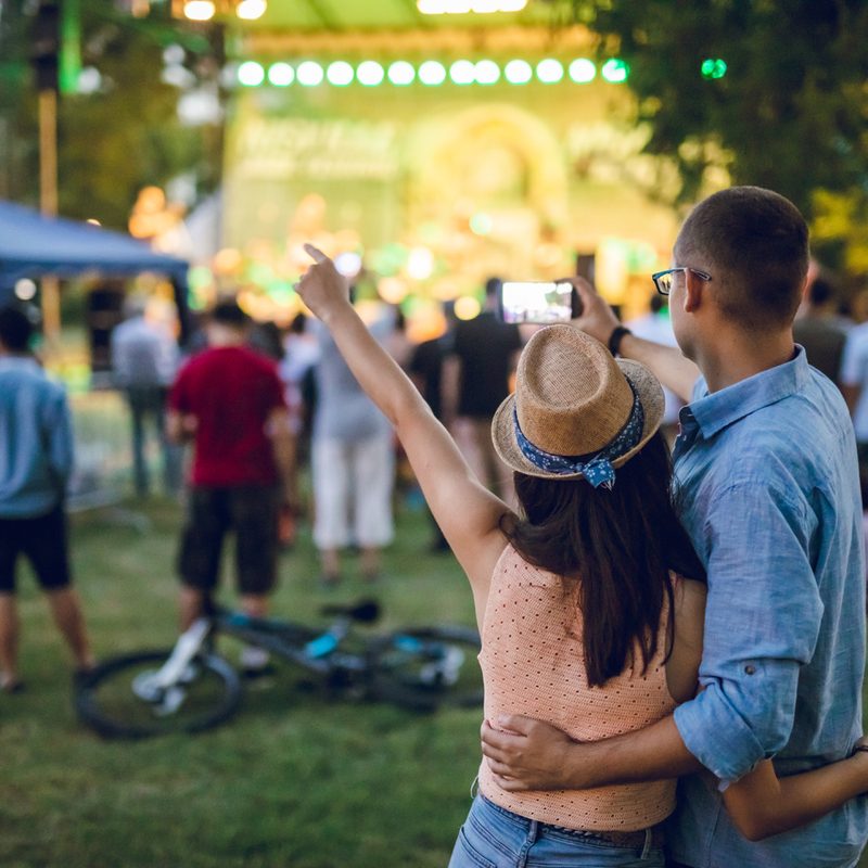 A couple taking a selfie during an outdoor concernt.