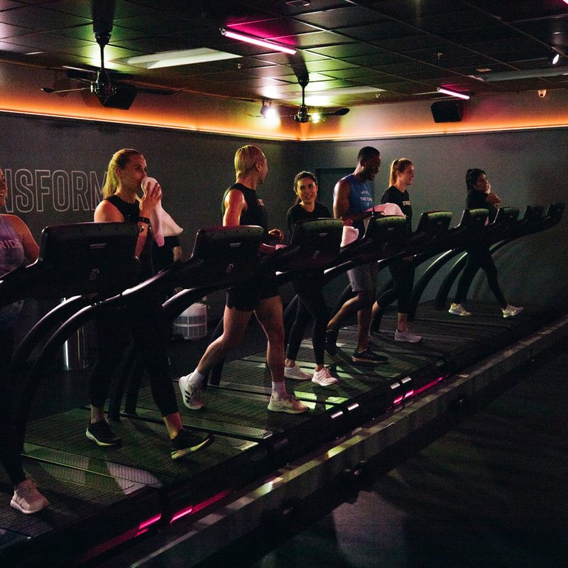 Male and female athletes running on treadmills at Stride Fitness