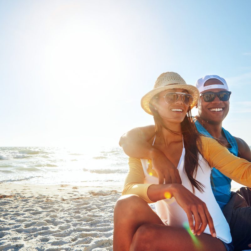 A couple with sunglasses taking a selfie at the beach.