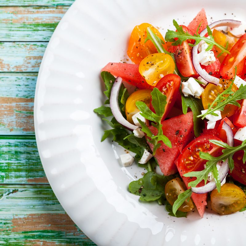 A plate of watermelon and tomato slices with Feta and balsamic sauce.