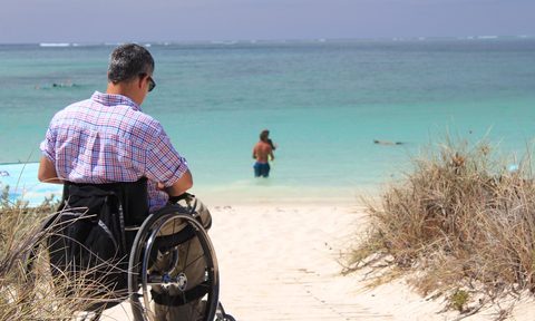 man in wheelchair by beach