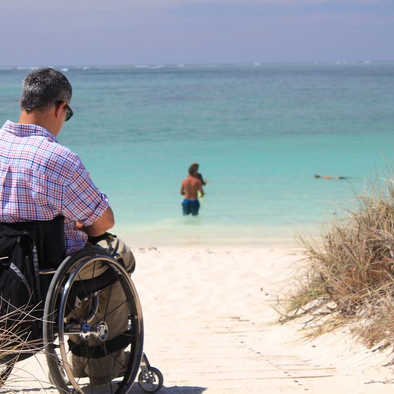 man in wheelchair by beach