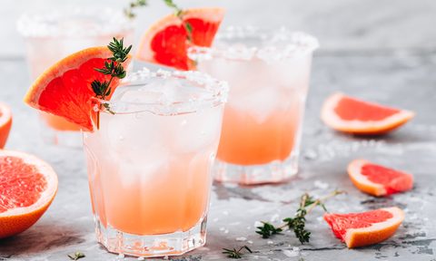 Grapefruit salty dog cocktail with ice in glass on gray stone background