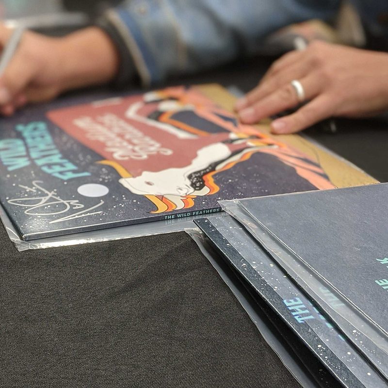 A worker signing a vinyl album on a table