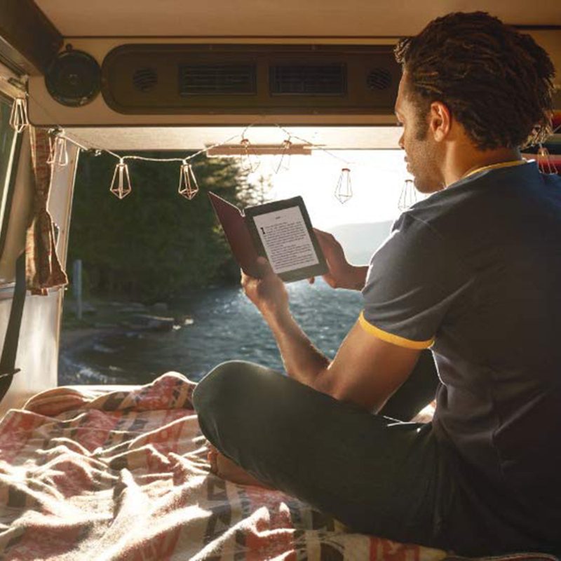 Man reading on Kindle Paperwhite in van.
