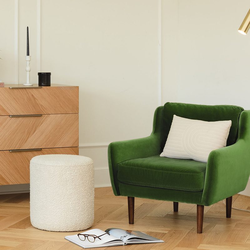 A Matrix Grass Green Chair beside a gold-colored lampshade and white round stool with a glasses on top of an opened book in a living room.