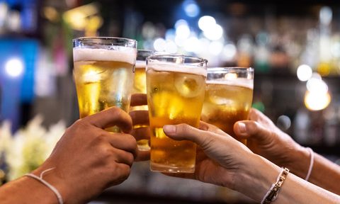Group of happy friends drinking and toasting beer at brewery bar restaurant.