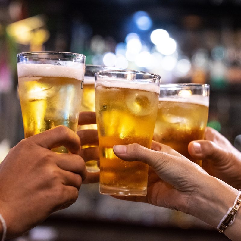 Group of happy friends drinking and toasting beer at brewery bar restaurant.