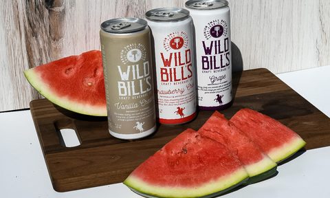A can of Wild Bill’s Vanilla Cream, Wild Bill’s Strawberry Cream, and Wild Bill’s Grape and slices of watermelons on a wooden cutting board.