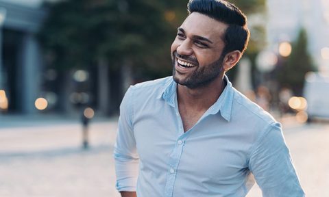 A smiling man wearing a blue shirt in the city
