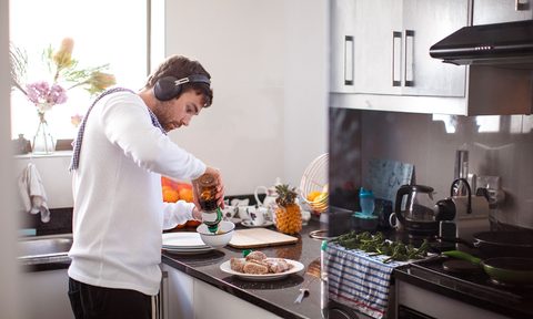Man wearing headphones cooking in kitchen.