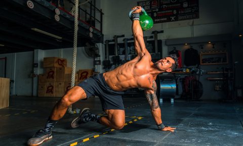 A man doing an oblique exercise with a kettlebell.