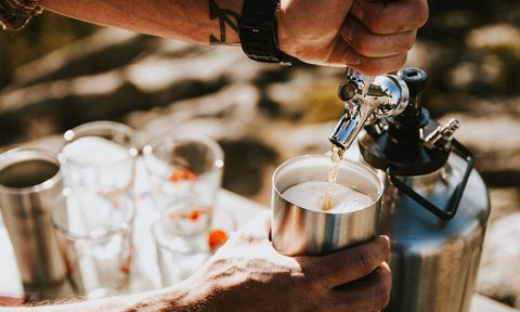 Man pouring a draft beer from a pressurized beer growler.