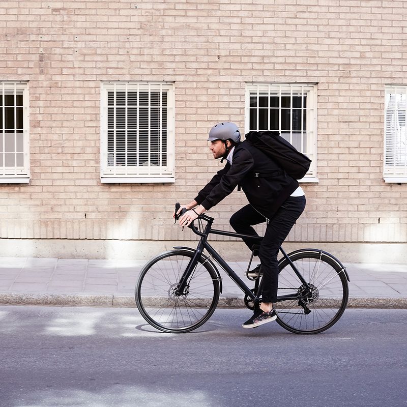 Man riding bicycle with building in background.