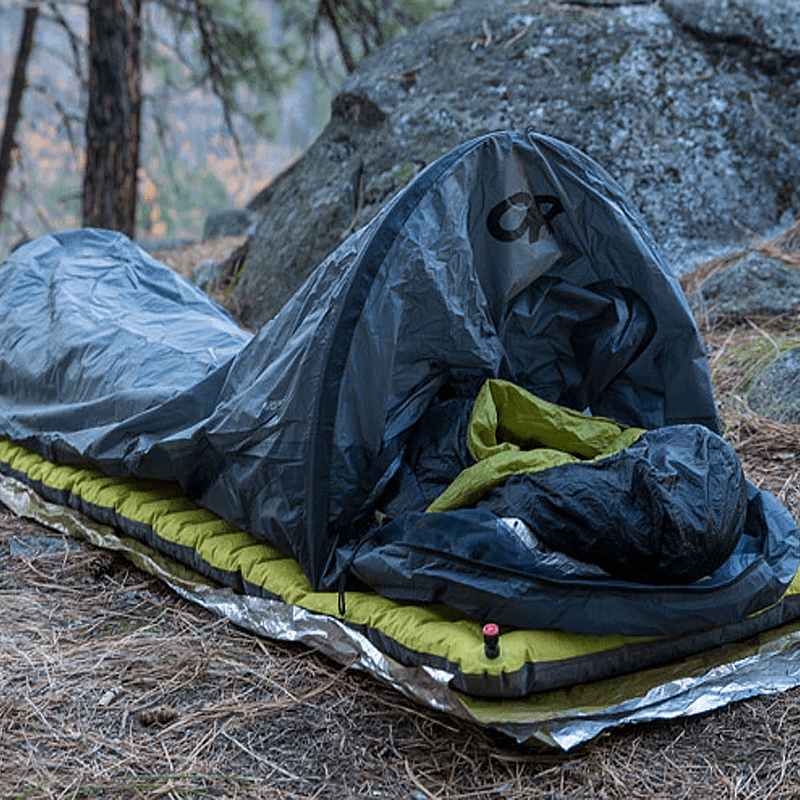 An opened bivy sack in a forest.