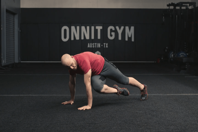 An athlete performing the crossover mountain climbers at the Onnit Gym.