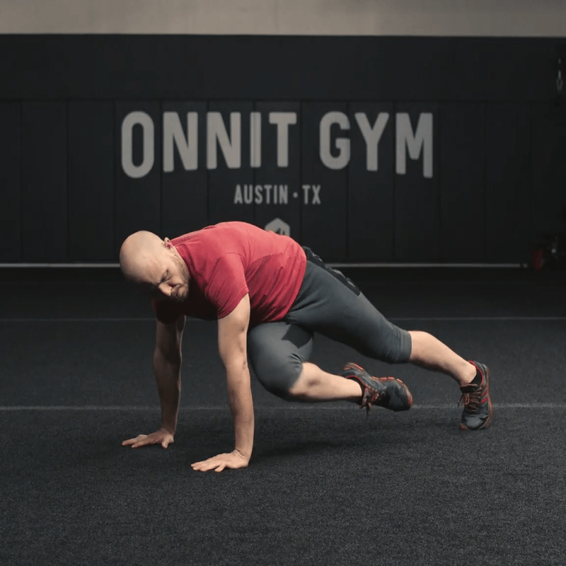 An athlete performing the crossover mountain climbers at the Onnit Gym.