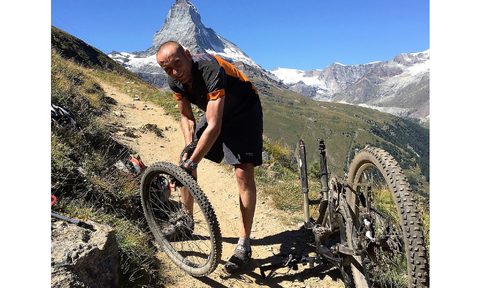 man fixing a bike tire on trail