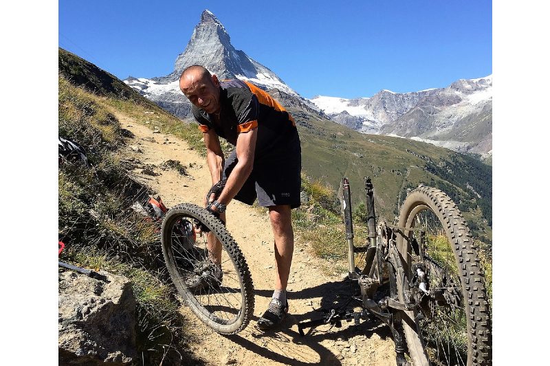 man fixing a bike tire on trail