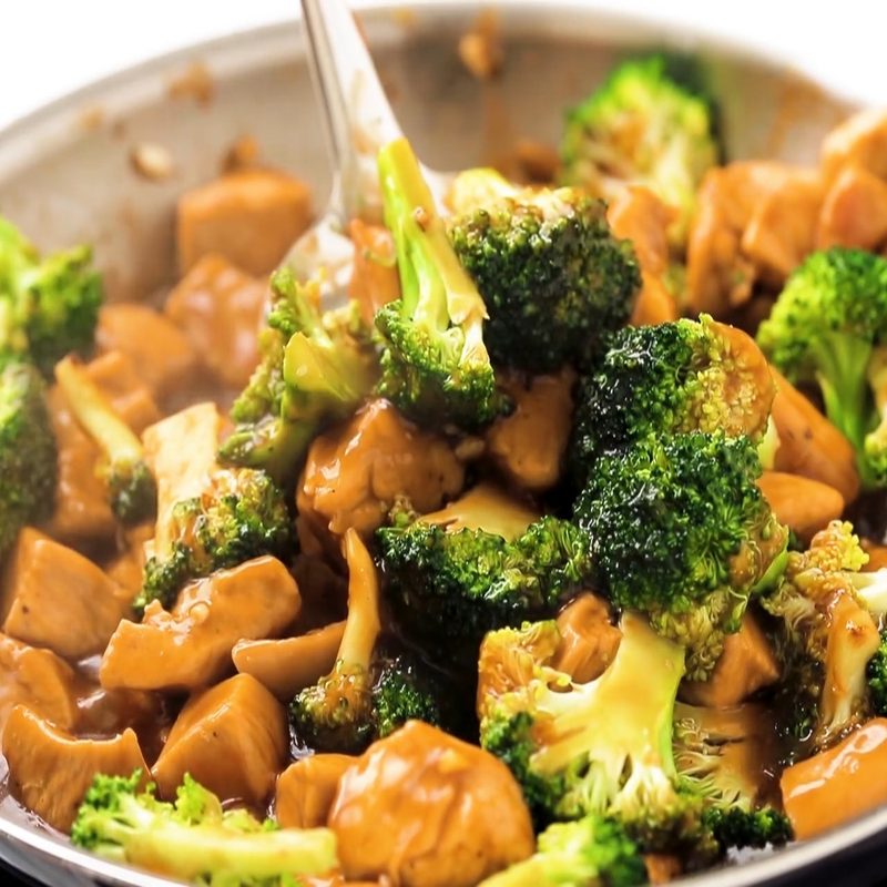 Chicken and broccoli stir fried in a pan.