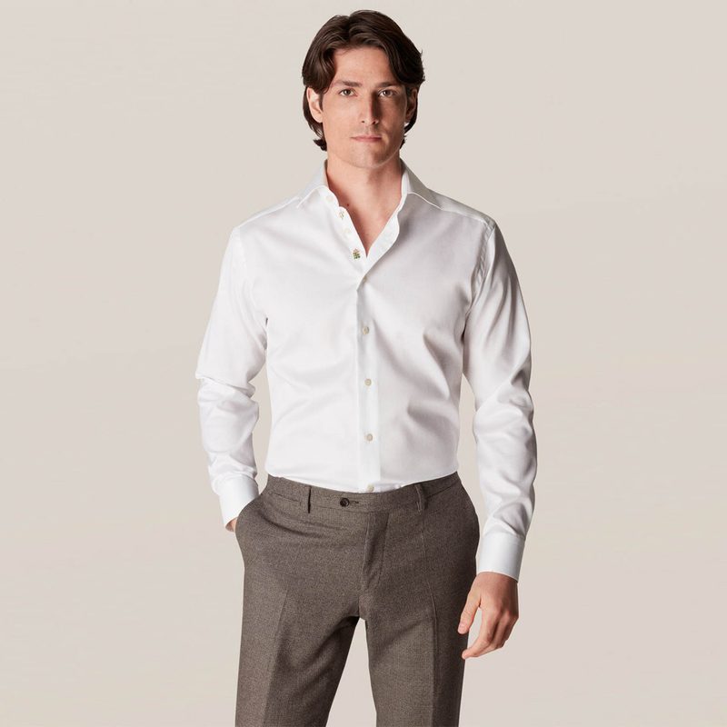 A male model with his hand in his pocket is seen wearing a white twill shirt from Eton.