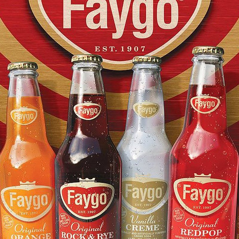 Assorted flavored bottles of Faygo soda displayed in front of the Faygo logo.