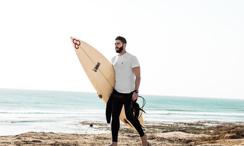 man with surf board walking on the beach.