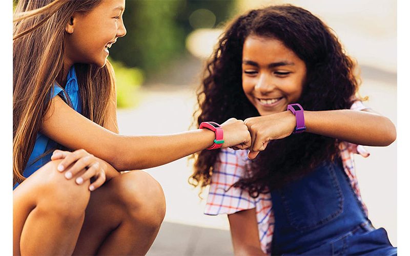 Two children wearing Fitbit Ace 2s and smiling.