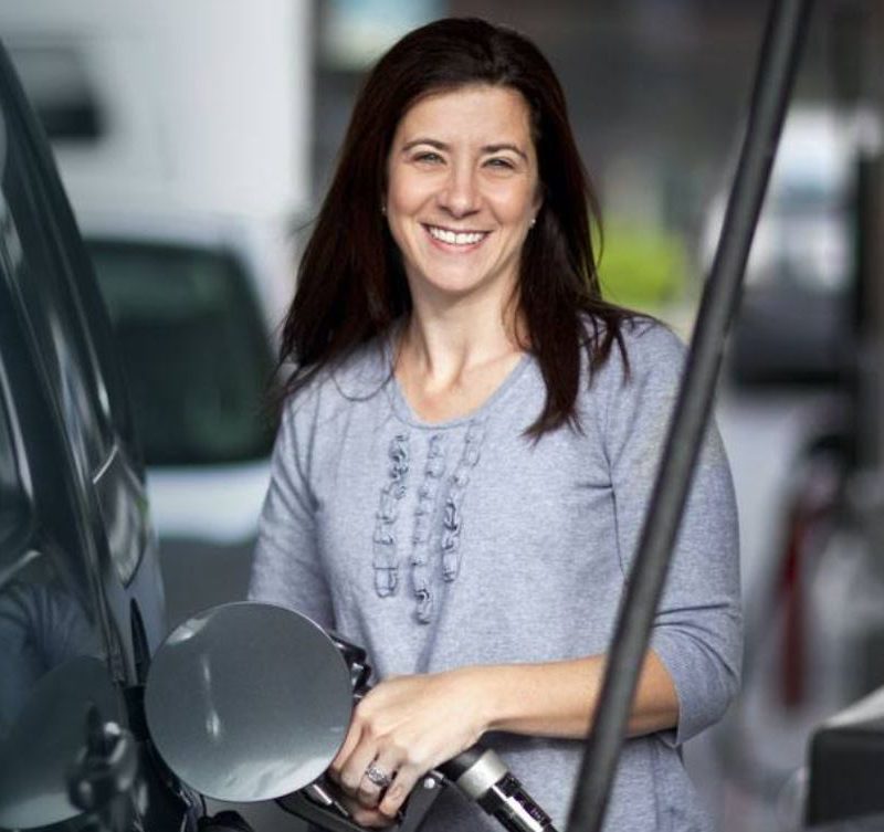 Woman using GasBuddy fuel rewards app to save money.