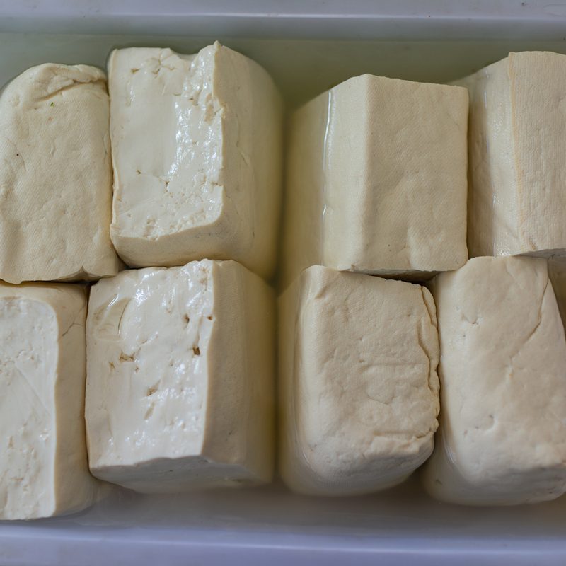 Cubes of tofu soaked in water in a plastic tray.